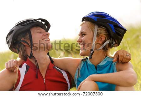 Cute couple with cycling helmets laugh together and have fun outdoors
