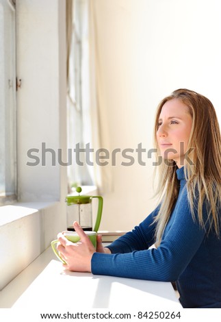 Beautiful woman stares out of the window while drinking her coffee