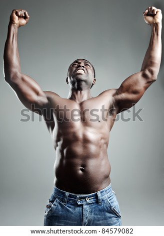 Well-built muscular black man with arms raised in studio