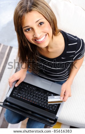 Woman is smiling and looking up to frame with laptop, after doing some online shopping