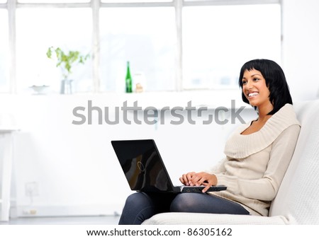 Indian woman sitting on the couch, typing on her laptop while thinking about her work
