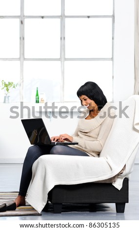 Indian woman sitting on the couch typing on her laptop