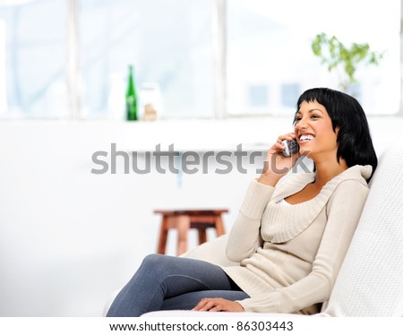 Young attractive woman sitting on the couch at home, chatting on the telephone
