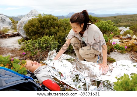 Medical emergency while hiking. woman has emergency blanket and her friend is calling for help