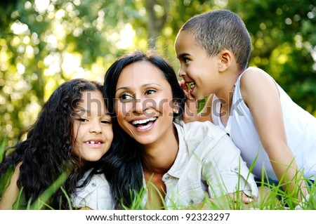 happy family outdoors on the grass in a park. mom and two children smiling
