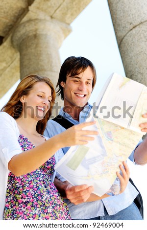 excited young couple traveling, they look at a map while visiting an old tourist attraction monument