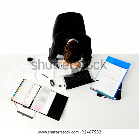 Man in business suit sits stressed out at his desk when he is faced with too much work