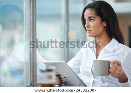 Young business woman investor using tablet computer for work in office with coffee