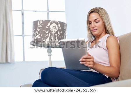 Woman at home relaxing on sofa couch reading email on the tablet computer wifi connection
