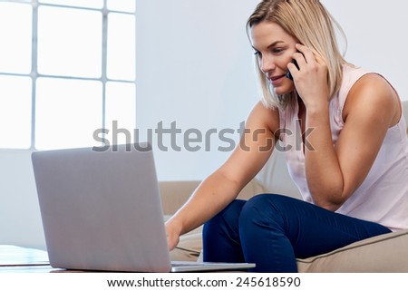 Woman sitting on sofa couch checking accounts and shopping online at home