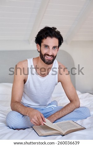 portrait of man relaxing on bed reading literature novel story book at home