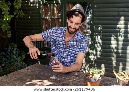 young man enjoying red wine outdoors in summer spring season backyard garden at home