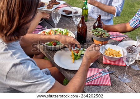 man dishing healthy fresh salad at outdoor barbecue garden party gathering