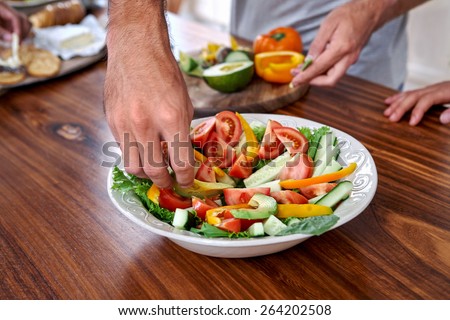 man making healthy fresh salad in kitchen