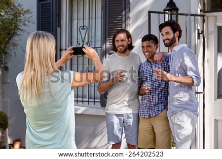 women taking photo pictures of group friends on mobile cellphone camera outdoors at garden party