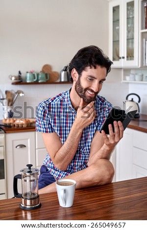 man enjoying french press filter coffee with mobile cellphone at home kitchen