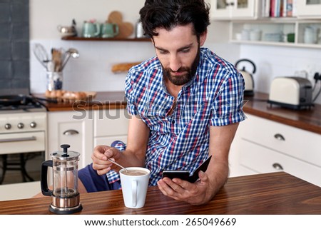 man enjoying french press filter coffee with mobile cellphone at home kitchen