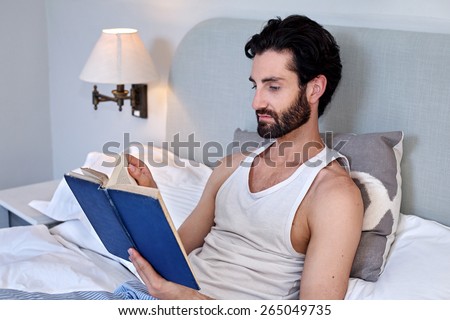 man relaxing on bed reading literature novel story book at home