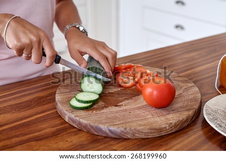woman making tomato and cucumber salad kitchen at home