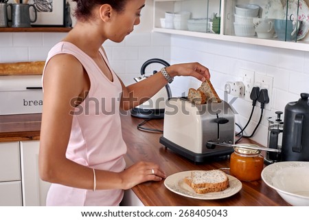 young woman making breakfast toast bread with toaster at home kitchen
