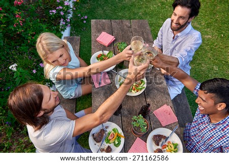Group of friends toasting to celebration with drinks at garden outdoors party