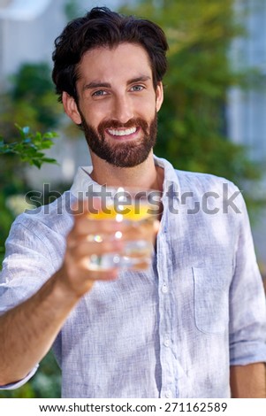 portrait of young man standing outdoors in garden with cocktail drink