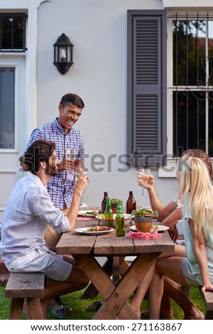 Man toasting speech at friends outdoor garden party with wine drinks