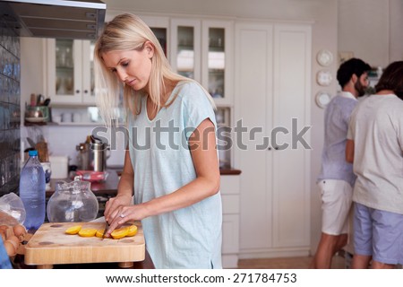 young woman carefully cutting fresh lemon at a friends gathering in kitchen at home