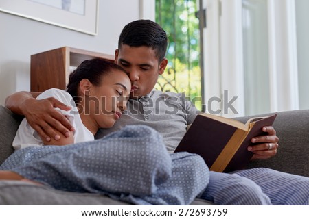 young husband kiss sleeping wife forehead in arms on sofa couch in home living room