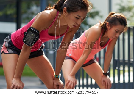 exhausted sporty asian chinese women runners after fitness running workout outdoors