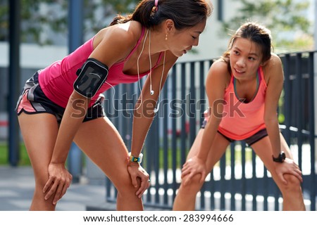 exhausted sporty asian chinese women runners after fitness running workout outdoors