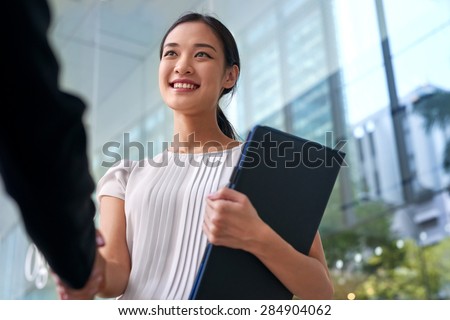 beautiful asian chinese business woman shaking hands in modern city work office