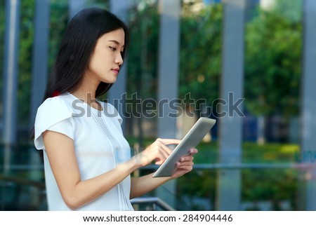 asian chinese business woman working on tablet computer in modern office