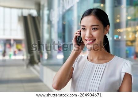 happy asian chinese business woman talking on mobile cell phone at work