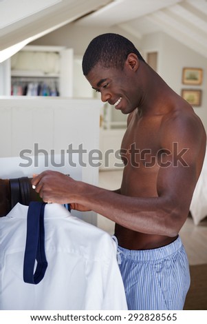 handsome african black man getting ready morning routine shirt and tie at home for work