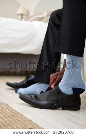 professional man getting ready for work putting formal smart shoes on for work in morning at home