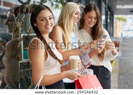 portrait of beautiful teen girl shopping in city with friends standing outdoors with mobile cell phone