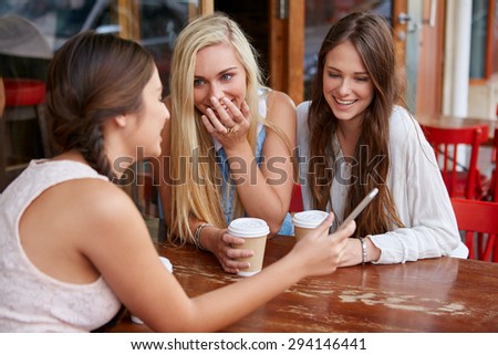 beautiful young girls having coffee at outdoor cafe with mobile cell phone