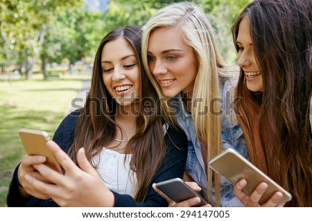 young friends watching viral social media video on mobile cell phone outdoors