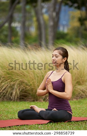 young woman in the park doing yoga pose meditating with praying hands