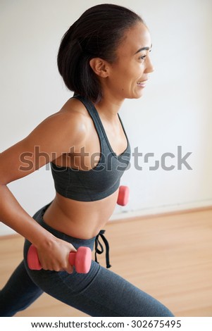 smiling fitness woman exercising with dumbbells at home indoors