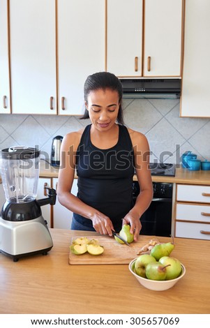 young female cutting fruits in kitchen preparing a smoothie