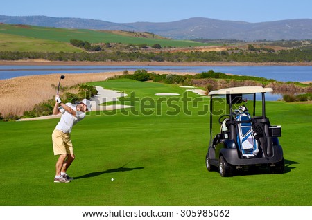 golf man playing shot with cart nearby on vacation