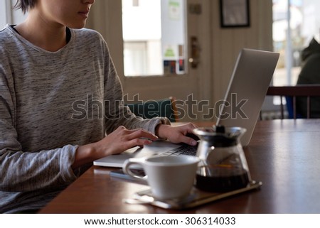 Asian Chinese woman busy on laptop, breakfast coffee