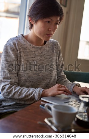 young woman sitting with open laptop computer on coffee break, surfing the net