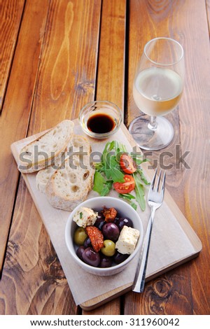 Platter with bread, olives, feta, side salad and a glass of wine