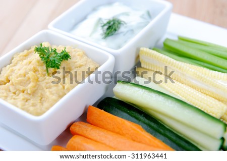 Tzatziki (yoghurt and cucumber) and hummus (chickpea) dips with raw carrot, cucumber, corn and celery