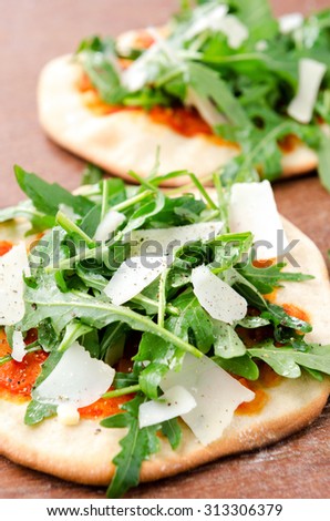 Mini pizzas with fresh rocket and shaved parmesan cheese