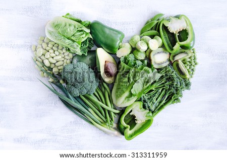Fresh green vegetables arranged in a heart shape, broccoli, broad beans, capsicum, kiwi, avocado, beans, peas, peppers for healthy living concept