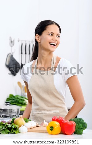 Happy mix race woman cooking and preparing food in the kitchen wearing a apron